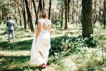First wedding meet in the garden. The meeting is newlyweds on a green field outdoors. Bride goes back to the groom, surprise in nature. Happy day of marriage. Wedding ceremony in forest.