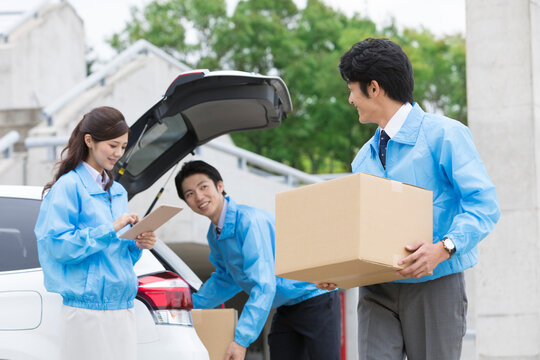 車から荷物を運ぶビジネス男女