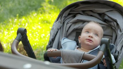 Mother and her happy baby outdoors, mom playing with six month old infant in the park on a summer day. High quality 4k footage