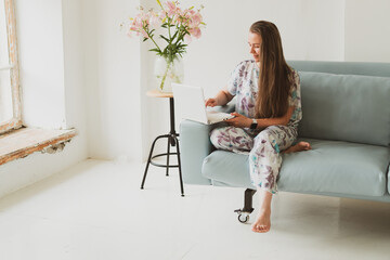 Fototapeta premium portrait of adorable young woman with laptop working at home while sitting on sofa