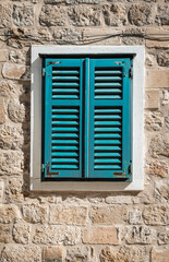 Fototapeta na wymiar Old window with closed shutters on exterior wall of a house in Dubrovnik, Croatia.