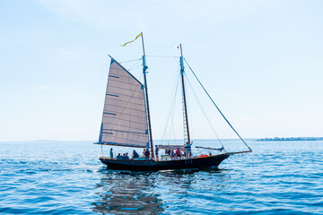 Fototapeta premium A yacht with two masts under sail with indistinguishable people sails slowly across the Atlantic Ocean