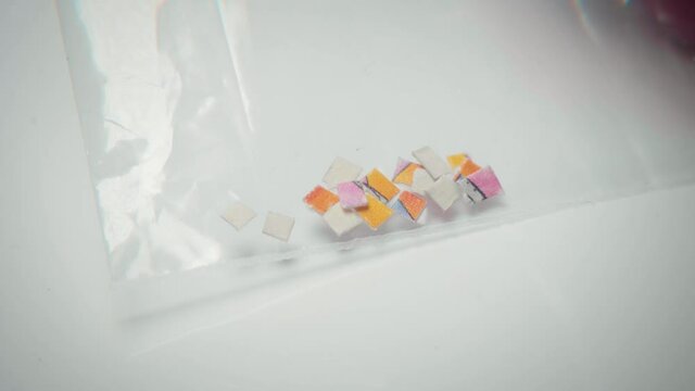 4K macro shot of LSD tabs in a plastic bag for microdosing usage.
