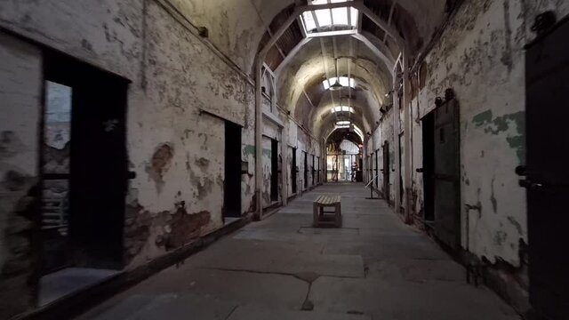 Camera moves down decrepit corridor of cellblock at Eastern State Penitentiary.