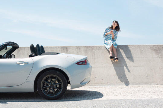 防波堤に座る女性と車