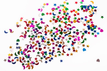 colored sequins in the form of hearts , stars and crescents on a white background