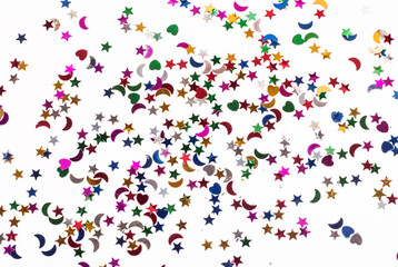 colored sequins in the form of hearts , stars and crescents on a white background