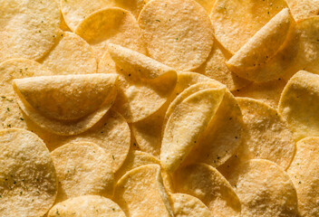 background of golden toasted potato chips with salt and spices