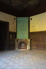 Vintage beautiful fireplace decorated with green ceramic tiles in the interior of a room in Sharovsky castle, Ukraine