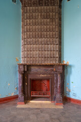 Vintage beautiful fireplace decorated with brown ceramic tiles in the blue room in Sharovsky castle, Ukraine