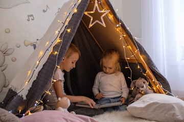 Obraz na płótnie Canvas Children are sitting in a hut and reading a book.