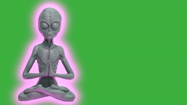 Neon Light pulsated around Grey Alien with closed eyes doing meditation with green screen in background - Copy Space