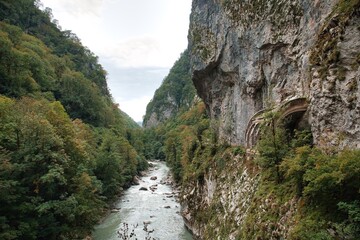 The mountain road runs along the cliff at the cliff. Rocks hang over the road and the abyss.