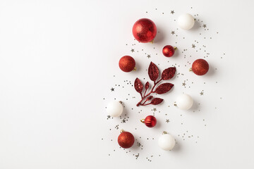 Top view photo of red and white christmas tree decorations branch balls and silver sequins on isolated white background with empty space