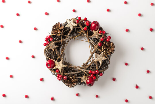 Top view photo of christmas twig wreath and scattered holly berries on isolated white background