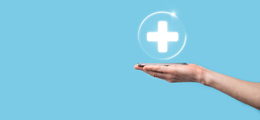 Obraz premium Businessman hold virtual plus medical network connection icons. Covid-19 pandemic develop people awareness and spread attention on their healthcare.