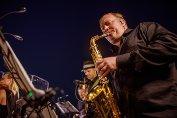 Fototapeta na wymiar Male musician playing saxophone under blue night sky
