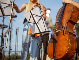 Musician with violoncello sitting near music note stand