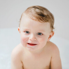 Cute adorable baby child taking bath in bathtub at home. Happy healthy boy or girl playing, splashing and having fun during bathtime. Hygiene and cleaning concept for babies.