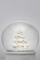 Close up of a white Christmas snow globe with white Christmas tree decorated with presents and...