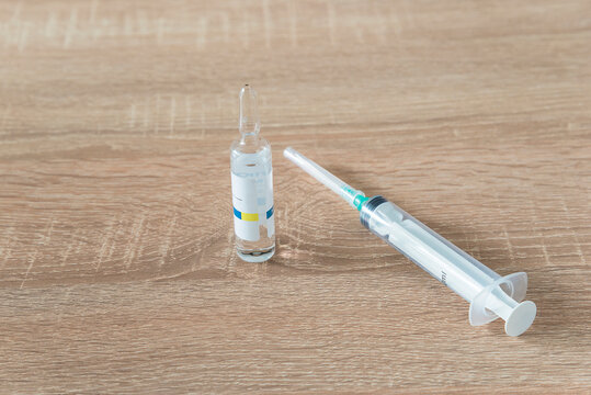 One ampoule and siringe on wooden background