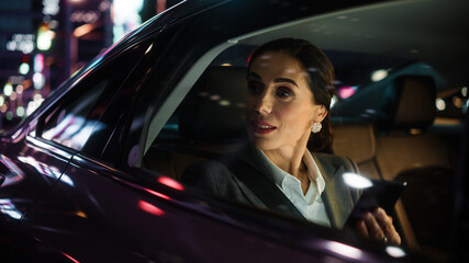 Beautiful Businesswoman is Commuting from Office in a Backseat of Her Car at Night. Entrepreneur...