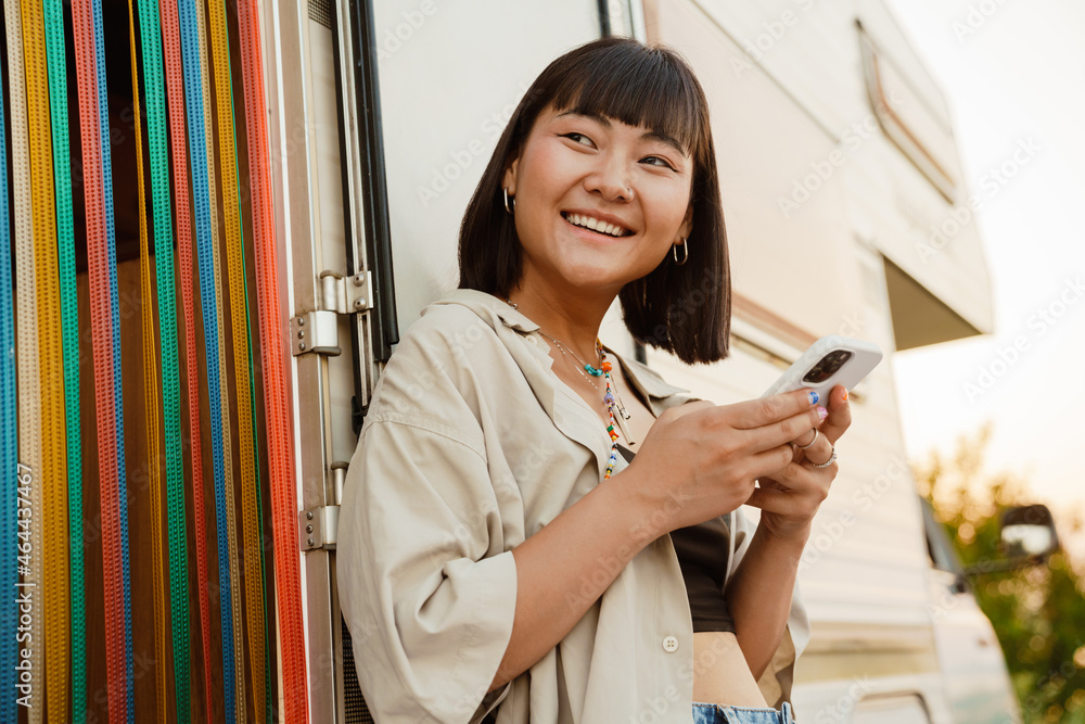 Wall mural asian young woman using cellphone while leaning on trailer