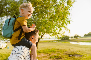 Young white father carrying son on shoulders while walking outdoors
