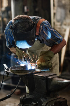 Industrial welder in protective mask working with torch he welding metal in the workshop