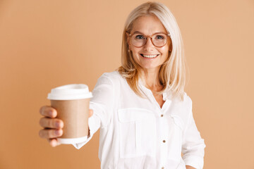 Mature woman in eyeglasses smiling while drinking coffee