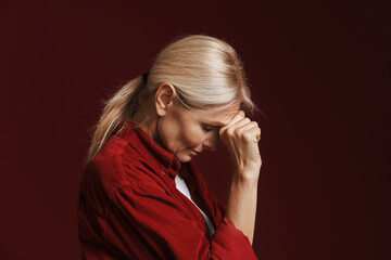 Mature blonde woman wearing shirt propping up her head