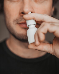 A man takes a nasal spray to cleanse his nose - treatment and prevention of a runny nose - relieving breathing - obrazy, fototapety, plakaty