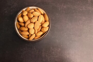 Almonds in white bowl on dark background. Almond Food or ingredient concept with copy space. Dry fruits background or festivals banners. Diwali gift concept.