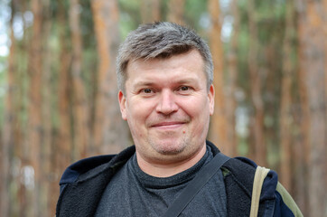 Portrait of a positive middle-aged man in front of a blur of tal