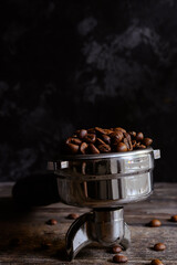 Fresh roasted coffee beans. Portafilter. Dark background.
