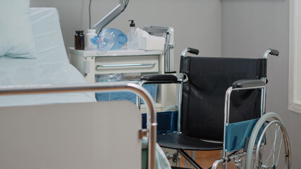 Empty hospital ward for healthcare and medical recovery. Nobody in intensive care space with wheelchair, IV drip bag and heart rate monitor. Emergency room with oxygen tube and medicine