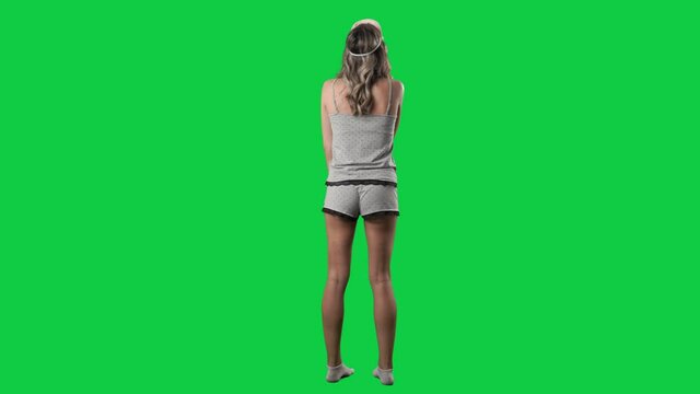 Amazed young woman in pajamas turning and looking around planning for home renovation. Full body isolated on green screen background