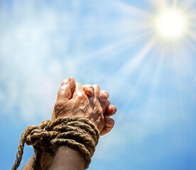 Rope tied hands on sky background