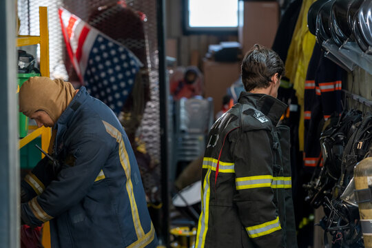 Firefighter ready for action,Fireman wearing firefighter turnouts and helmet in storage room with fireman safety gear in fire department.