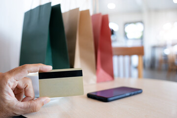 Select focus on hand holding credit card with shopping bags and mobile phone on table