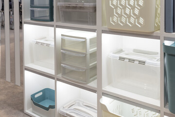 Plastic container boxes on a shelf on a rack for organizing home space and storing things, order and interior, selling household goods. Industrial background