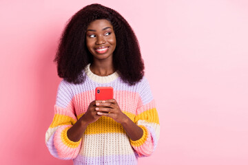 Portrait of positive dark skin blogger look empty space hold phone toothy smile isolated on pink color background