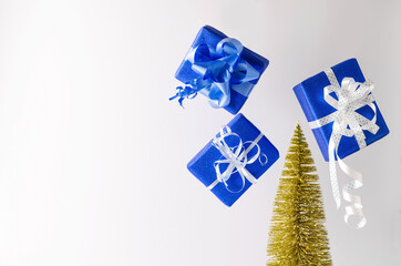 Levitation of Christmas, New Year gifts in blue paper and eco tree on white background, empty background. Boxing day concept, give gifts