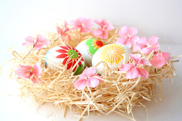 
Multicolored Easter eggs with applique lie in a nest of shavings on a white background. Copy space. Festive easter banner.Selective focus. 
