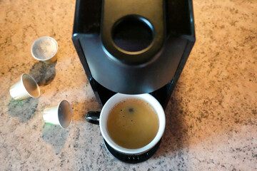 Top view of black coffee capsule machine, coffee cup with coffee and coffee pods