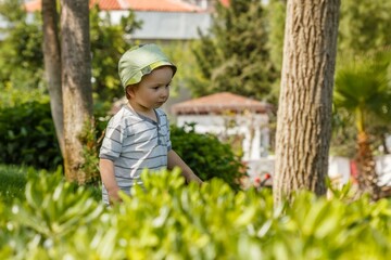 Boy on green grass lawn in summer park,  caucasian.