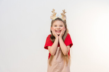 A beautiful little girl in a Christmas outfit is smiling.