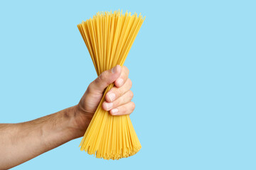 Spaghetti pasta in hand on a blank background. Raw Italian spaghetti before cooking and eating...