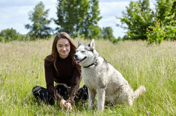 Owner girl playing with her siberian husky at field. Happy smiling woman with dog have a good time on weekend activity outdoors
