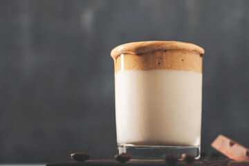 Whipped Dalgona coffee drink in a glass with milk, dark background